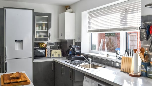 Una cucina moderna con lavatrice integrata, dispenser di acqua, tostapane e macchina del caffè.