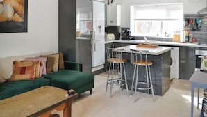 Una cucina moderna con isola centrale, sgabelli da bar e un divano verde con cuscini.