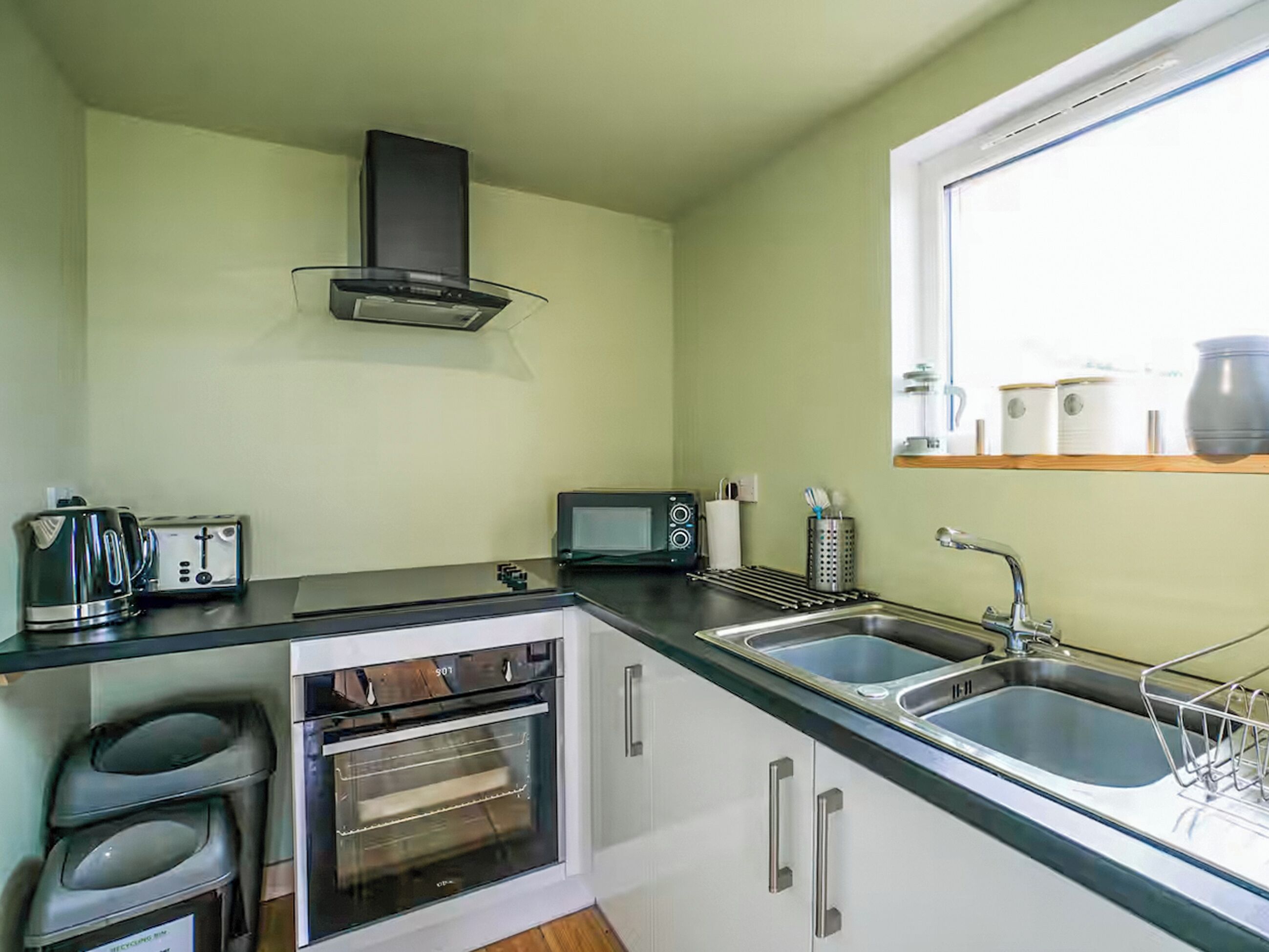 A compact kitchen with a toaster, microwave, oven, and sink.