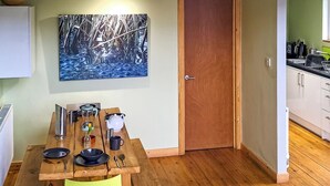 A dining area with a wooden table, chairs, and a painting on the wall. - Glamping made easy near Kielder: eco design, family fun, and endless stars. (Hexham, near Bellingham)