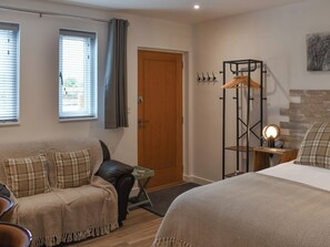 Ein Hotelzimmer mit Bett, Sofa, kleinem Tisch, Kleiderständer und einer Tür.