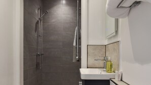 Un baño moderno con ducha, lavabo y espejo.