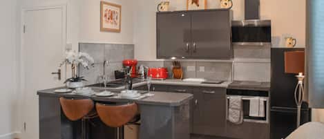 Une cuisine moderne dotée d’un îlot central, de tabourets de bar et d’un coin repas.