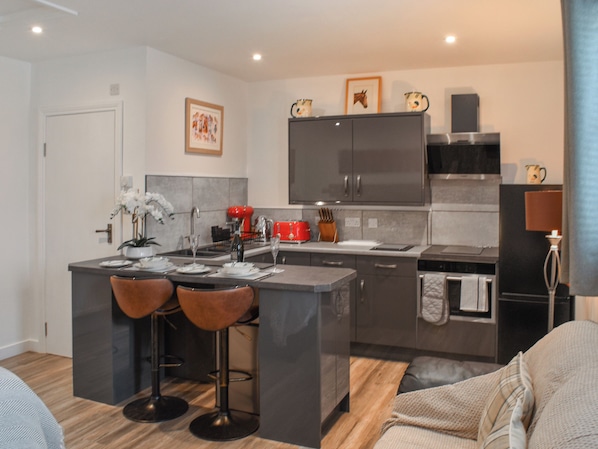 Una cocina moderna con una isla central, taburetes de bar y una zona de comedor.