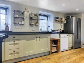 Una cocina moderna con armarios grises claros, encimera negra, refrigerador de acero inoxidable y ventana con vistas.