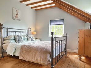 Un dormitorio con cama, piso de madera, una ventana y un aparador de madera.
