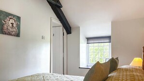 Una camera da letto con un letto, cuscini, una finestra e un quadro appeso al muro.