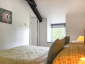 Ein Schlafzimmer mit Bett, Kissen, einem Fenster und einem Bild an der Wand.