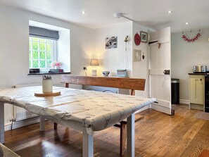 Una cocina con una mesa de comedor, un ventanal con vistas, una lámpara y un reloj en la pared.