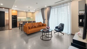 A modern living room with a sofa, a coffee table, and a TV stand. - Regal Residences Tay ho (Hanoi)