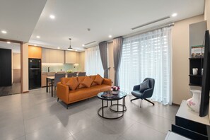 A modern living room with a sofa, a coffee table, and a TV stand. - Regal Residences Tay ho (Hanoi)