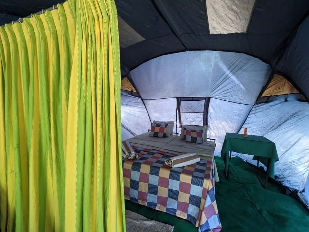 Uma tenda com cama, almofadas e uma mesa.
