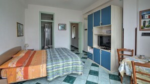 Een slaapkamer met een bed, een bureau, een stoel en een kledingkast.