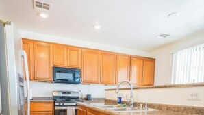A kitchen with wooden cabinets, stainless steel appliances, and a tiled floor.