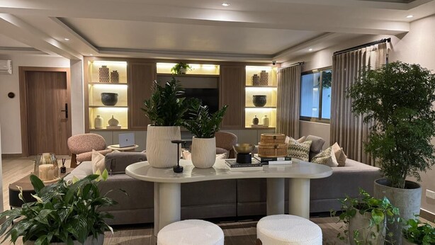A modern living room with a central island, seating area, and a dining space.