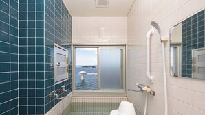 Un bagno con vasca, WC e una finestra vista mare.