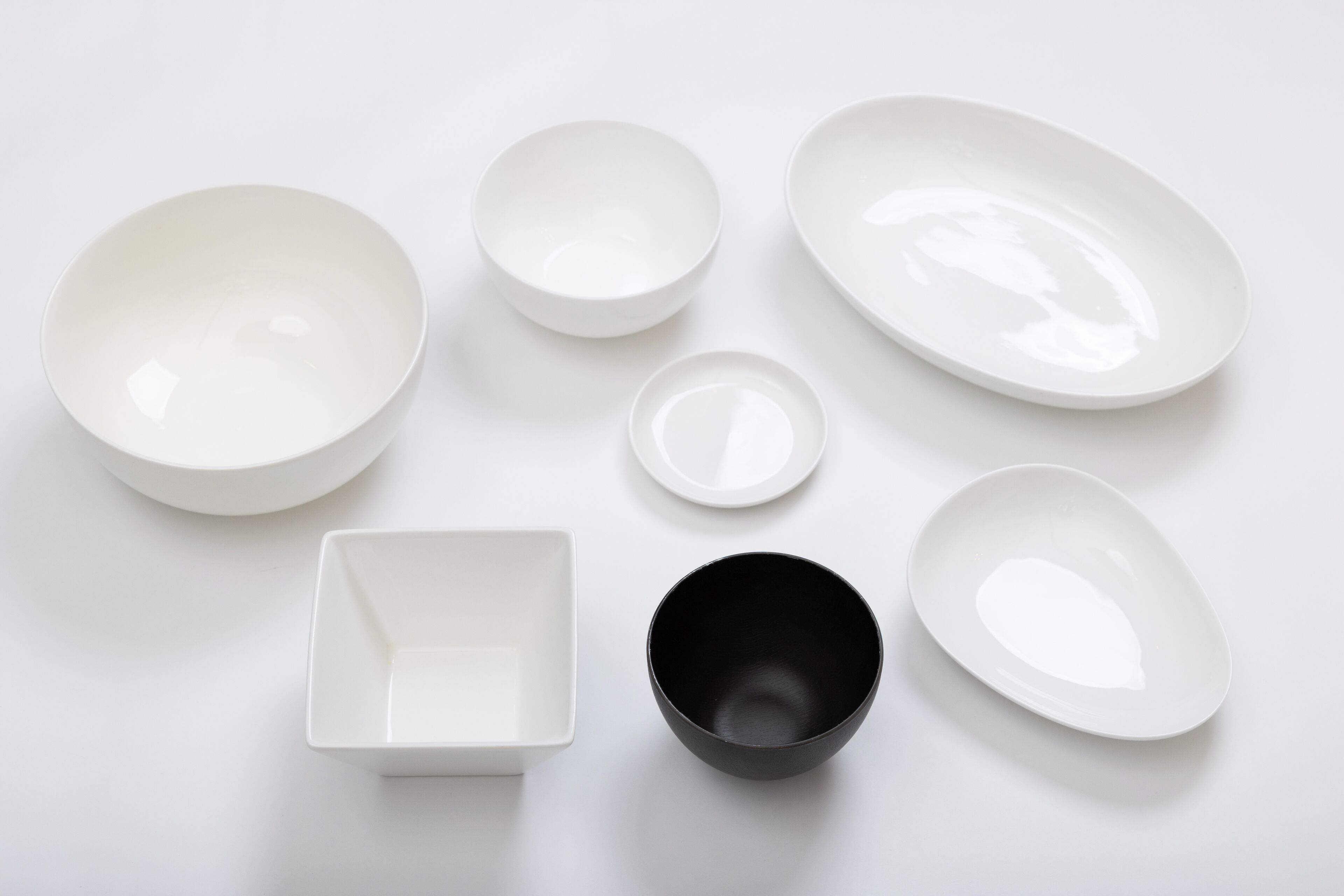 Un conjunto de cuencos y platos blancos y negros dispuestos sobre una superficie blanca.