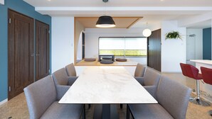 Zona pranzo moderna con tavolo in marmo, sedie rivestite in grigio e lampada a sospensione.