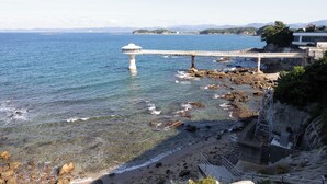 Paesaggio costiero con un ponte, un litorale roccioso e una costruzione simile a un faro.