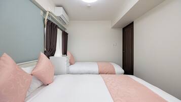 A bedroom with two beds, a nightstand, and a window with curtains.