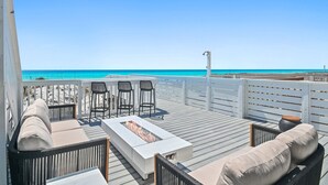 A deck with a fire pit, outdoor seating, and a view of the ocean.