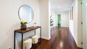 A hallway with a console table, two stools, a mirror, and a door leading to a bathroom. - GuestReady – Madeira escape with ocean view (Funchal)