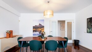 A dining area with a wooden table, teal chairs, a vase with flowers, and a landscape painting on the wall. - GuestReady – Madeira escape with ocean view (Funchal)