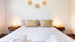 A neatly made bed with two pillows, two bedside tables with lamps, and three wall decorations. - GuestReady – Madeira escape with ocean view (Funchal)