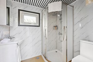 A modern bathroom with a glass-enclosed shower, a white sink, and a mirror with a black frame. - Bus Life, Sleep, Play & Farm Views (Fyansford)
