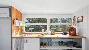 A compact kitchen with a wooden countertop, a sink, and a window with a view of greenery.