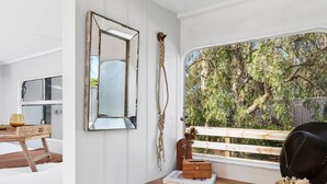 A room with a wooden desk, a mirror, and a view of trees through a window.