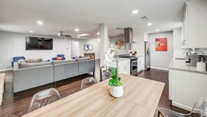 Una cocina moderna con armarios blancos, una mesa de comedor de madera y una orquídea en maceta.