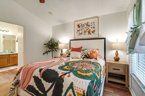 A bedroom with a large bed, two bedside tables, a nightstand, a mirror, and a window with curtains. - Private Pool & Golf Cart! Villa By Spanish Springs (The Villages)
