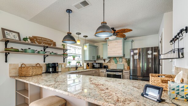 A kitchen with a marble countertop, hanging pendant lights, and a ceiling fan. - Private Pool & Golf Cart! Villa By Spanish Springs (The Villages)