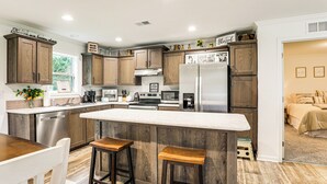 Eine moderne Küche mit Holzschränken, Edelstahlgeräten und einer zentralen Kochinsel mit Hockern.