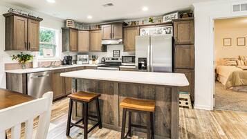 A modern kitchen with wooden cabinets, a large island, and stainless steel appliances.