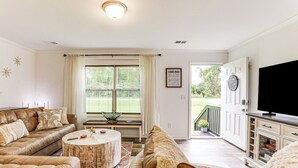 Ein Wohnzimmer mit einem braunen Ledersofa, einem runden Couchtisch und einem Fernseher auf einer Anrichte.