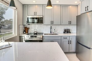 A modern kitchen with grey cabinets, stainless steel appliances, and a large island.