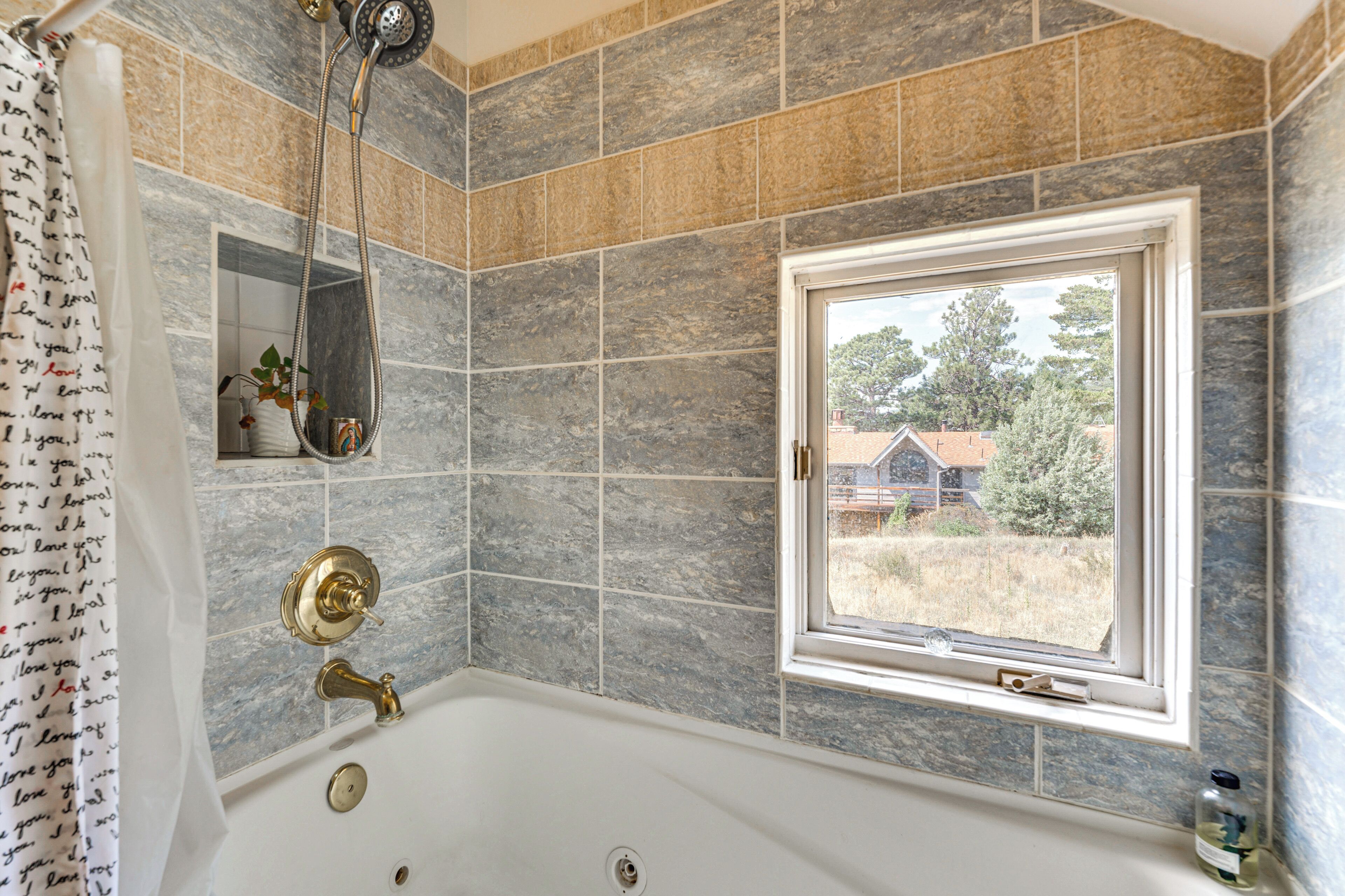A bathroom with a bathtub, a window, and a shower.