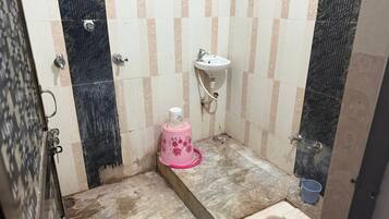 Un baño pequeño con inodoro, lavamanos y un cubo de basura rosa.