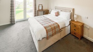 A bedroom with a bed, a nightstand, a lamp, and a view of the outside. - You’ll love the spacious layout, perfect for families or groups. (Brigg)