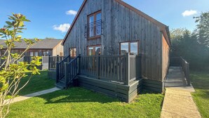 A wooden building with a balcony, a staircase, and a pathway leading to it. - You’ll love the spacious layout, perfect for families or groups. (Brigg)