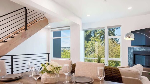 Un comedor moderno con escalera de madera, ventanas amplias y chimenea.