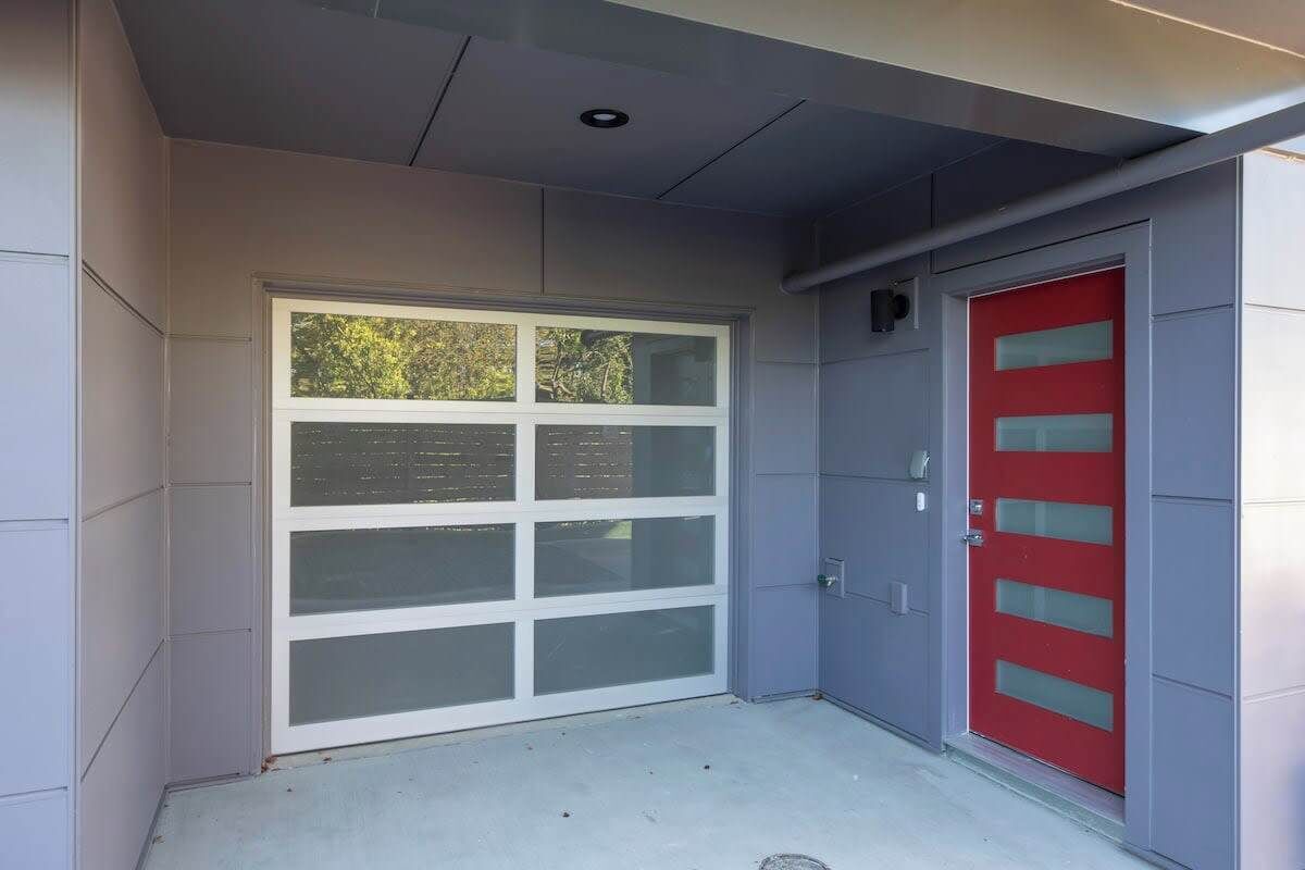 A garage door with a window, a red door, and a grey wall.