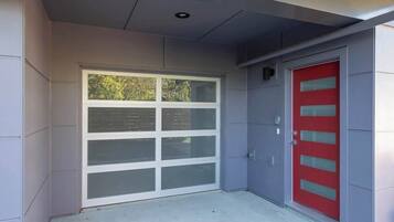 A garage door with a window, a red door, and a grey wall.