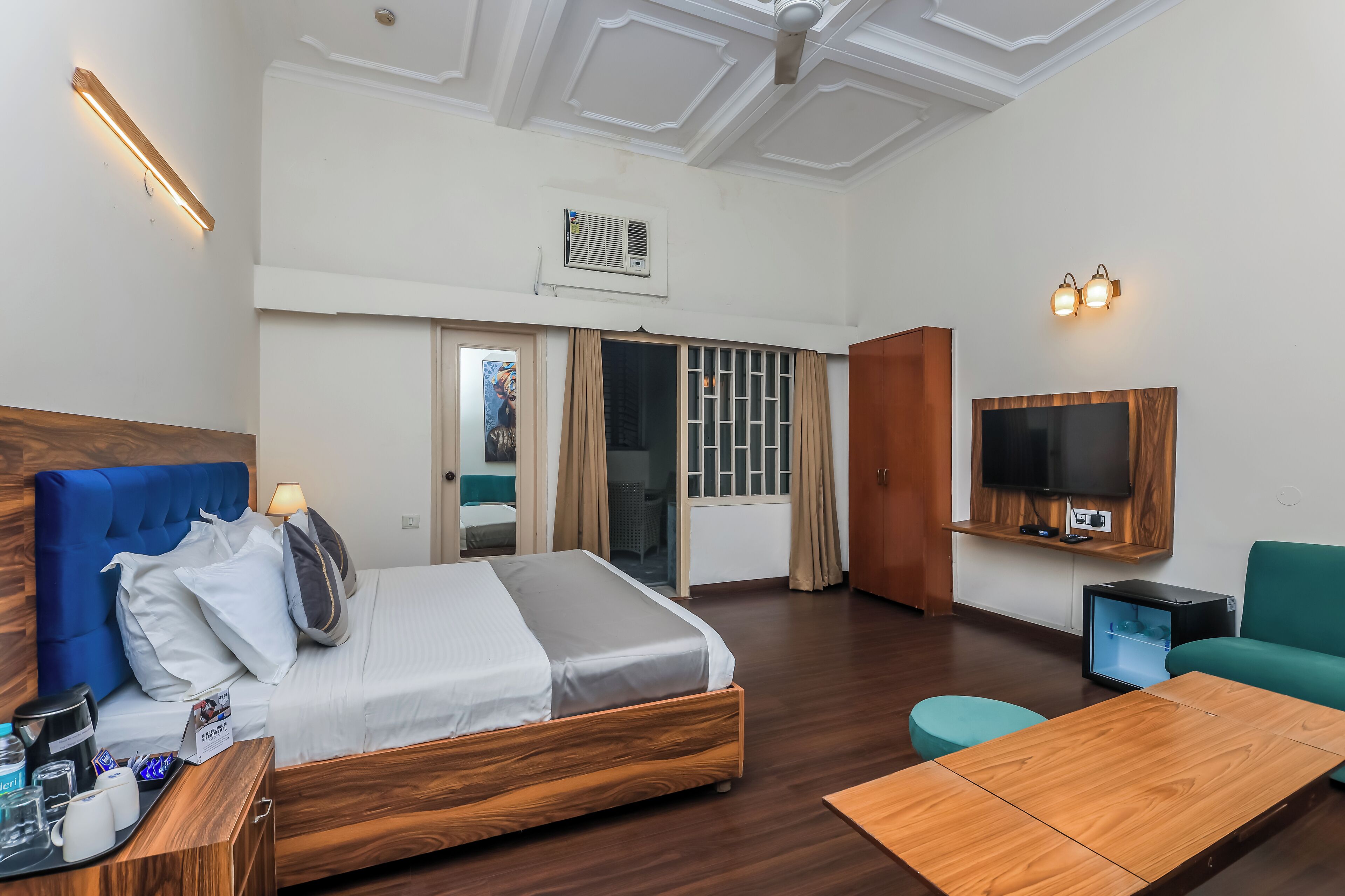 A hotel room with a bed, wooden headboard, bedside table, and a TV mounted on the wall.