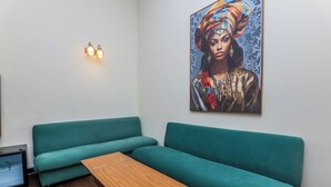 A teal sofa, a wooden table, and a wall-mounted artwork. - asar CP Outer Circle by Orion Hotels (New Delhi)