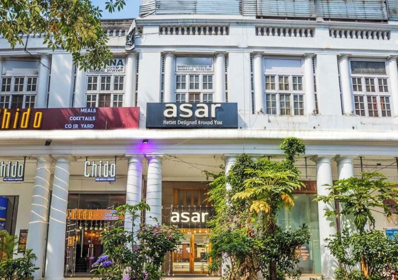 A building with multiple storefronts, including 'Chido' and 'asar' with signs indicating 'Meals, Cocktails, Coir Yard'.