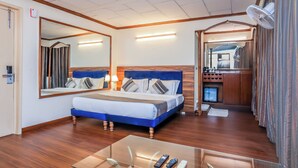 A hotel room with a large bed, a bedside table with a lamp, a mirror, and a small kitchenette. - asar CP Outer Circle by Orion Hotels (New Delhi)