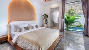Ein modernes Schlafzimmer mit einem großen Bett, einem Holz-Kopfteil, einer Zimmerpflanze und Blick auf einen Swimmingpool durch das Fenster.